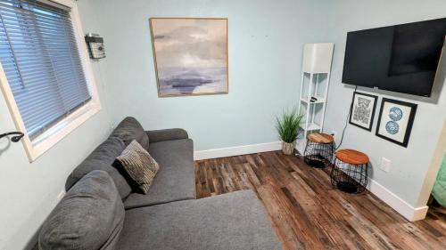 a living room with a couch and a flat screen tv at 1964 Earthquake Cottage - Slumber Village 10 in Anchorage