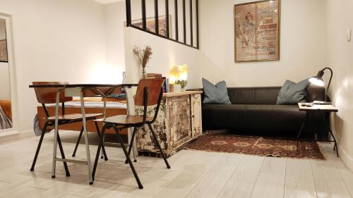 ein Wohnzimmer mit einem Sofa, einem Tisch und Stühlen in der Unterkunft Cosy Studio aux Batignolles - Proche Montmartre in Paris