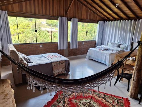 a room with a hammock and two beds in it at Aconchego da Beth in Camanducaia