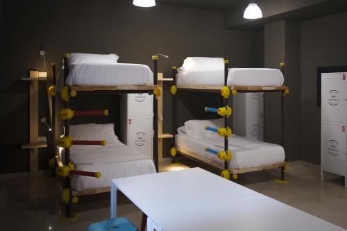 a room with three bunk beds and a table at Hostelò - Luxury Hostel in Palermo