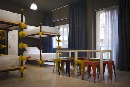 巴勒摩的住宿－Hostelò - Luxury Hostel，客房设有两张双层床和一张桌子及椅子。