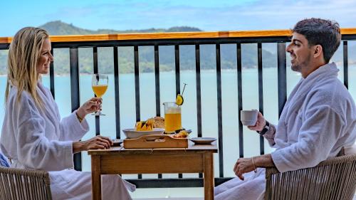 un uomo e una donna seduti a un tavolo con bevande di Catalina Hotel a Ubatuba