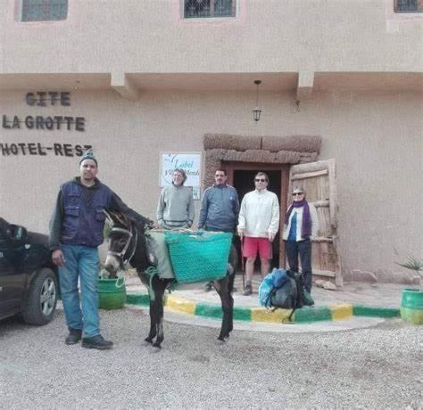 un grupo de personas de pie en frente de un edificio con un burro en GITE LA GROTTE VALLEE, 