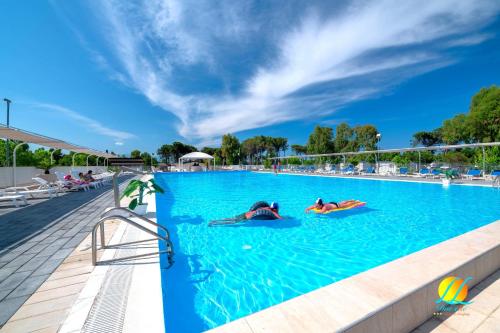 2 persone che nuotano in una grande piscina di Village Due Elle a Marina di Schiavonea