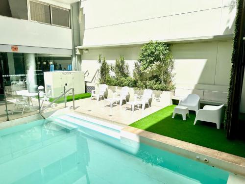 a swimming pool with white chairs and tables and a building at Ayres Recoleta Plaza in Buenos Aires