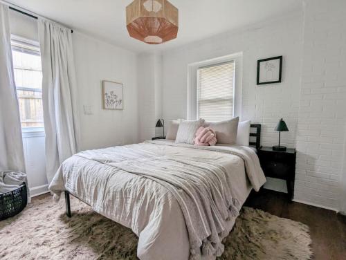 Dormitorio blanco con cama grande y almohada rosa en Stylish Retreat - 4 Min Downtown, en Greenville