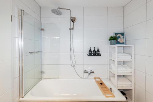 uma casa de banho branca com um chuveiro e uma banheira em Ferienwohnung "Kapellmeister" mit Klimaanlage in allen 4 Schlafbereichen, großes Wohnzimmer mit Smart TV und Big Sofa em Magdeburg