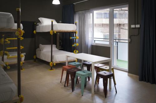 a room with bunk beds and a table and chairs at Hostelò - Luxury Hostel in Palermo