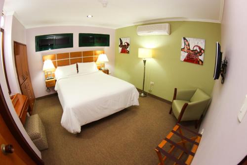 a bedroom with a white bed and a chair at Santa Fe Inn Hotel in Punto Fijo