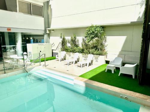 a swimming pool with white chairs and tables and a building at Guido 1980 by Ayres Apartments Recoleta in Buenos Aires