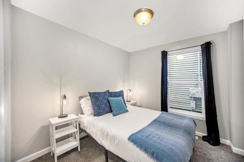 a white bedroom with a bed and a window at The Downtown Delight - New Corporate Apt Downtown in Grand Rapids