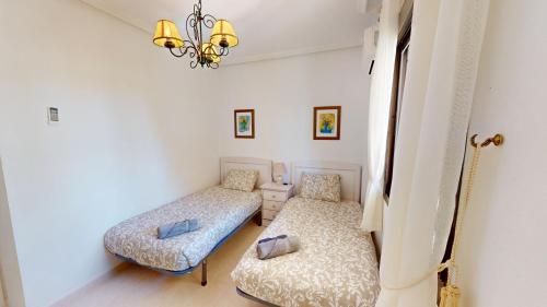 een kamer met 2 bedden en een kroonluchter bij Holidoo "Playa III" in Los Alcázares