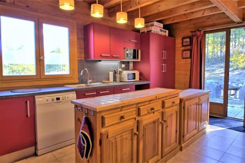 a kitchen with red cabinets and a white appliance at CASA-Forêt Blanche splendid chalet 13p in Risoul