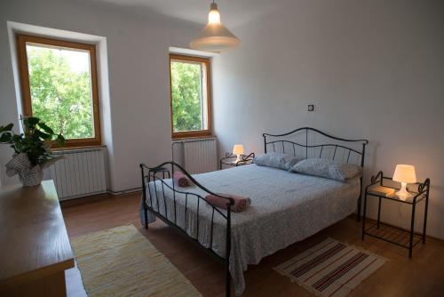 a bedroom with a bed with two tables and two windows at Country House Casa Lucia in Vodnjan