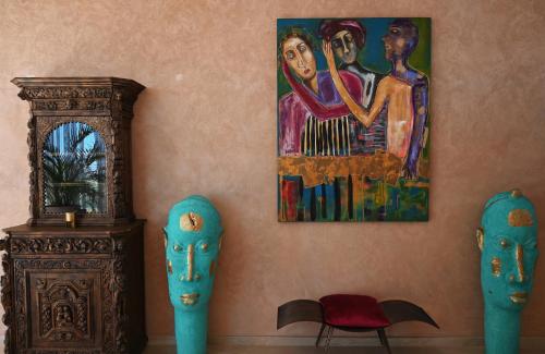 a wall with two blue masks and a painting at Maison Kenoosha Boutique Hotel & Spa in Marrakech