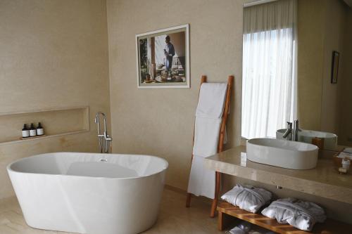 La salle de bains est pourvue d'une grande baignoire blanche et d'un lavabo. dans l'établissement Maison Kenoosha, à Marrakech