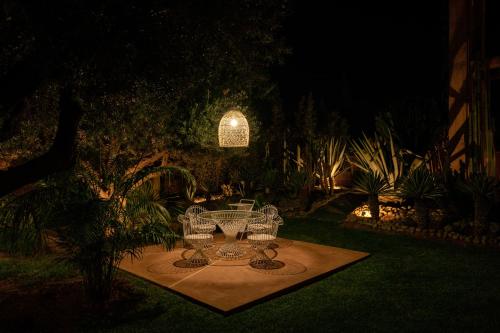 a table and chairs in a garden at night at Maison Kenoosha Boutique Hotel & Spa in Marrakech