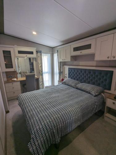 a bedroom with a bed with a blue head board at Luxury Caravan Littlesea Haven Frontline Fleet Lagoon Views in Weymouth
