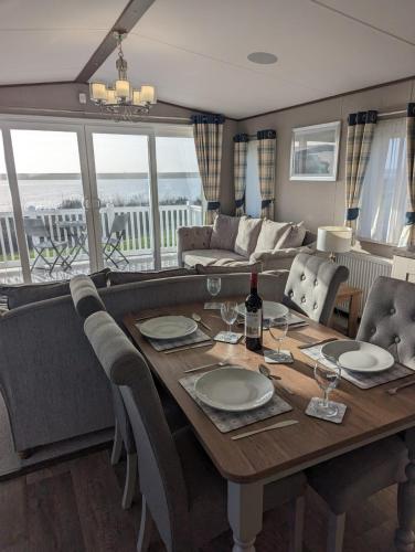 a dining room with a table with chairs and a couch at Luxury Caravan Littlesea Haven Frontline Fleet Lagoon Views in Weymouth