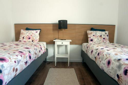 a bedroom with two beds and a night stand with a table at InTune Peniche Property in Peniche