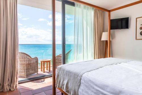 sypialnia z łóżkiem i widokiem na ocean w obiekcie Langley Resort Fort Royal w mieście Deshaies