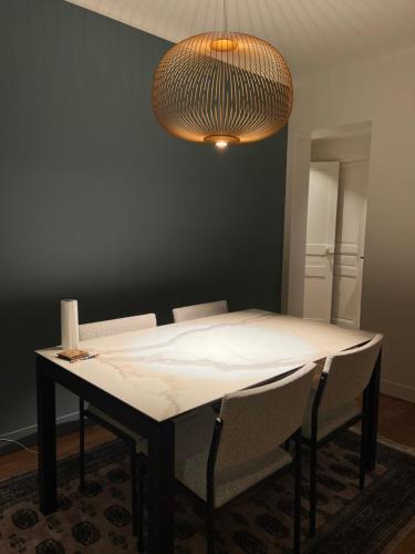 uma mesa de jantar com cadeiras e um candeeiro em 70m2 Cosy Apartment Daguerre em Paris