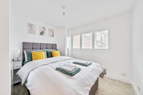 Stylish Contemporary 1 Bed Flat Near London Bridge في لندن: غرفة نوم بيضاء مع سرير مع وسائد خضراء وصفراء