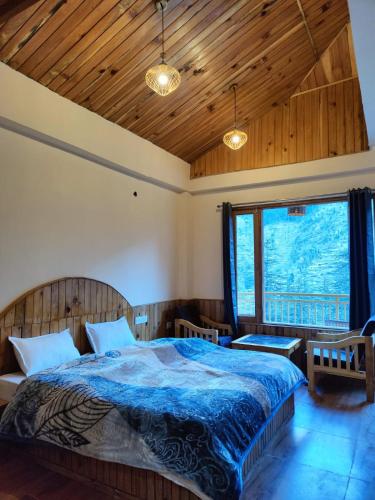 a bedroom with a bed and a large window at The Woodpecker Inn Jibhi in Jibhi