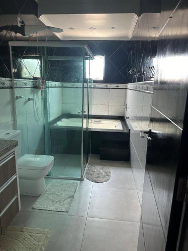 a bathroom with a glass shower and a toilet at Casa de Praia in Imbituba