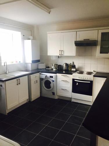 uma cozinha com armários brancos e piso em azulejo preto em The Poacher em Stevenage