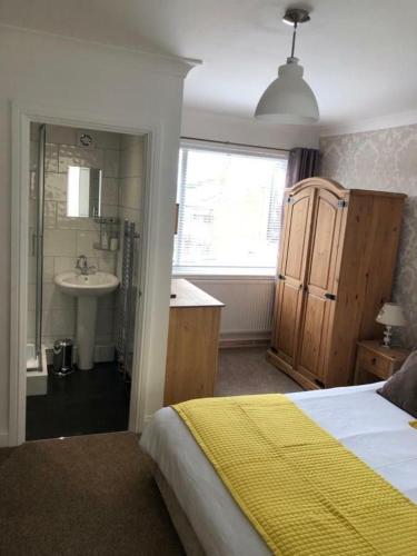 a bedroom with a bed and a bathroom with a sink at The Poacher in Stevenage