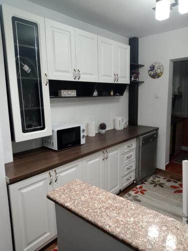 uma cozinha com armários brancos e uma bancada em Penti Apartament em Suceava