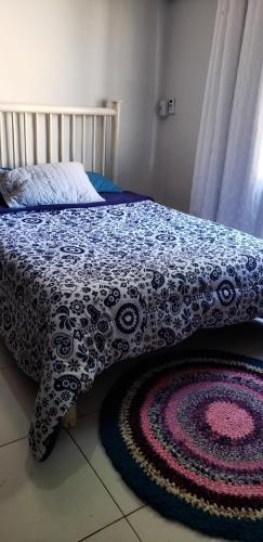 a bed with a blue and white blanket and a rug at Casa verde in Campo Grande