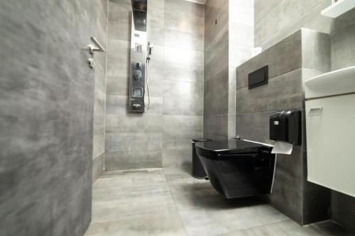 a bathroom with a black toilet and a shower at Hotel Gloria KS in Prishtinë