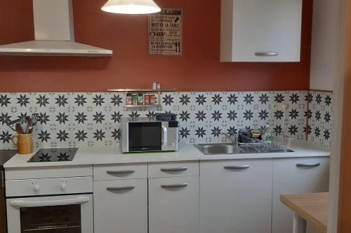 a kitchen with white cabinets and black and white tiles at Charmante maison à la campagne 