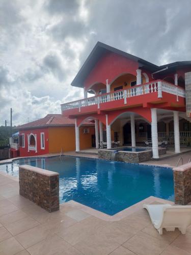 a hotel with a swimming pool in front of a building at Aqua Lounge in Sangre Grande