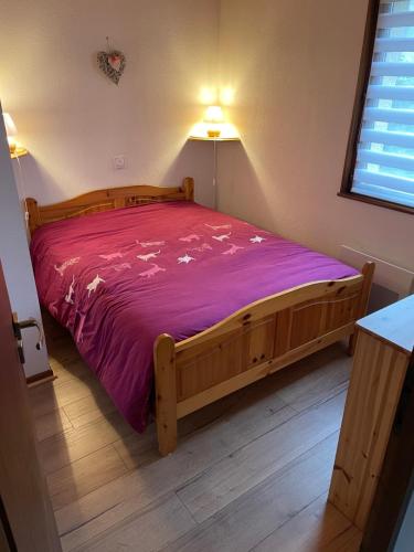 a bedroom with a large bed with a purple blanket at Cocon des chaumes in La Bresse