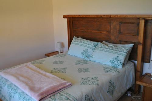 a bed with a wooden headboard and two pillows at Sunflower Cottage in Herbertsdale