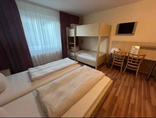 a room with two beds and a desk and a table at Autohof Hotel Salzbergen in Salzbergen