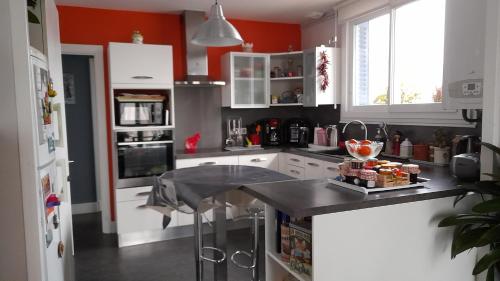 une cuisine avec des armoires blanches et un comptoir noir dans l'établissement Les Abélias, à Hauterive