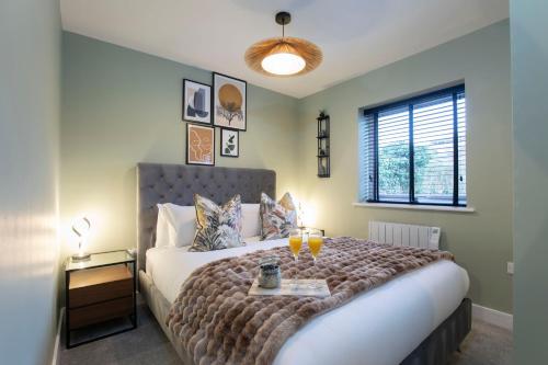 a bedroom with a bed with two drinks on it at Elliot Oliver - Deluxe Two Bedroom Apartment With Parking & EV Charger in Cheltenham