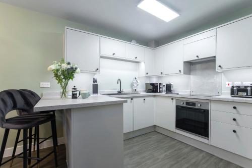 a white kitchen with white cabinets and a counter at Elliot Oliver - Deluxe Two Bedroom Apartment With Parking & EV Charger in Cheltenham