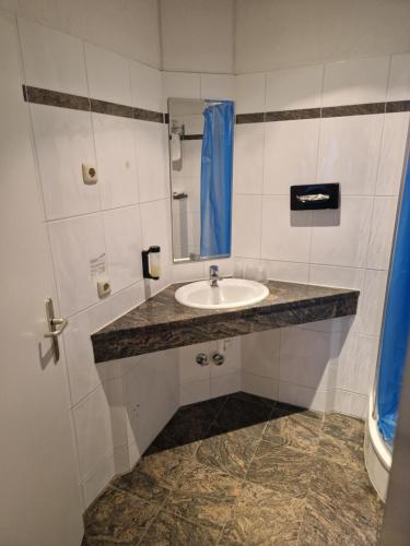 La salle de bains est pourvue d'un lavabo et d'un miroir. dans l'établissement Entrée Glinde Restaurant & Tagungshotel, à Hambourg