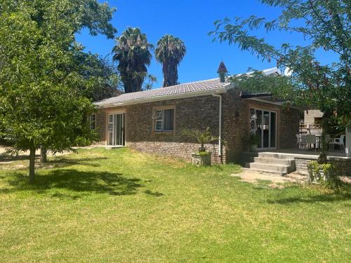 a small brick house with trees in the yard at Stay@51 Botha in Oudtshoorn