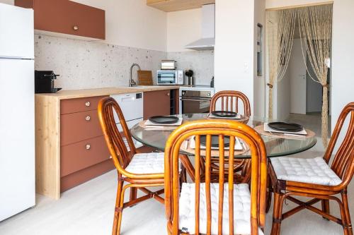 une cuisine avec une table en verre et quatre chaises dans l'établissement La vie en Rose, à Narbonne