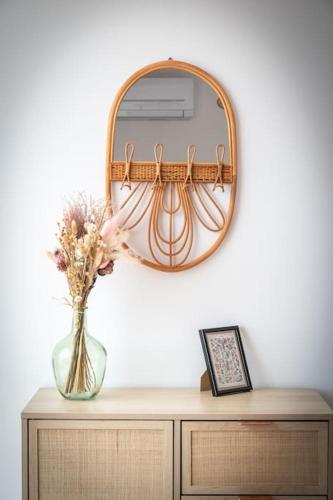 un vase de fleurs sur une commode avec un miroir dans l'établissement La vie en Rose, à Narbonne