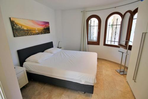 um quarto com uma cama branca e 2 janelas em Villa Ensueño em Calonge