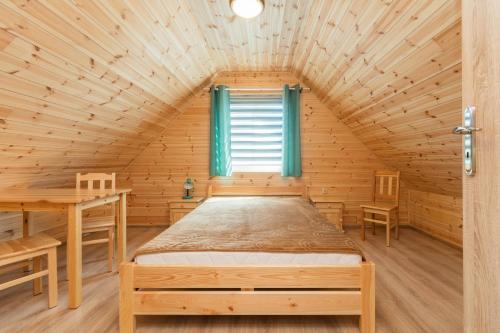 a bed in a wooden room with a window at Domek 7 osobowy piętrowy in Stegna
