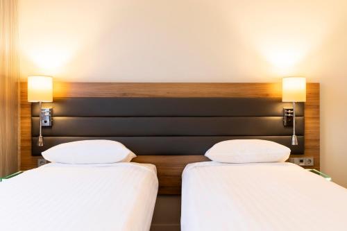duas camas num quarto de hotel com lençóis brancos em Moxy York em York