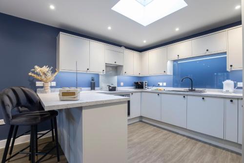 a kitchen with white cabinets and a skylight at Elliot Oliver - Exquisite Two Bedroom Apartment With Garden, Parking & EV Charger in Cheltenham